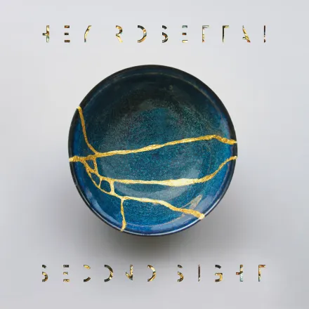 A blue ceramic bowl repaired with veins of gold, on a pale grey ground. The band name above and the title below are cut out of the ground in a stencil face, the gaps filled with the same gold and blue.
